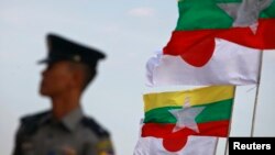 A police officer stands on guard near national flags of Myanmar and Japan during the commencement ceremony of the Thilawa Special Economic Zone (SEZ) project in the Japanese Special Economic Zone at Thilawa outside Yangon November 30, 2013. The first pha