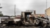 Residents walk past the wreckage of a burned vehicle following clashes in the streets of Goma, Democratic Republic of Congo, on Jan. 28, 2025.