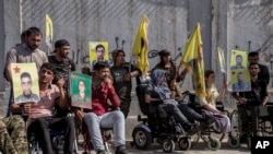 Wounded Kurdish fighters hold portraits of comrades who were killed fighting against IS militants, during a demonstration outside the U.N. building in Qamishli, northeast Syria, against an anticipated Turkish incursion, Oct. 8, 2019.