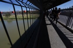 FILE - FILE - People walk back to Mexico on the Americas International Bridge, a legal port of entry which connects Laredo, Texas in the U.S., with Nuevo Laredo, Mexico, July 18, 2019.