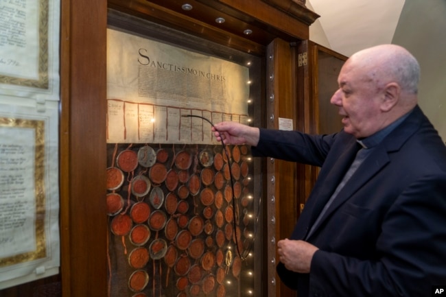 Bishop Sergio Pagano shows the original 1530 letter kept in his office at The Vatican, Feb. 14, 2024, that attempted to pressure Pope Clement VII into granting the divorce to King Henry VIII from his wife Catherine of Aragon that was denied. (AP Photo/Domenico Stinellis)