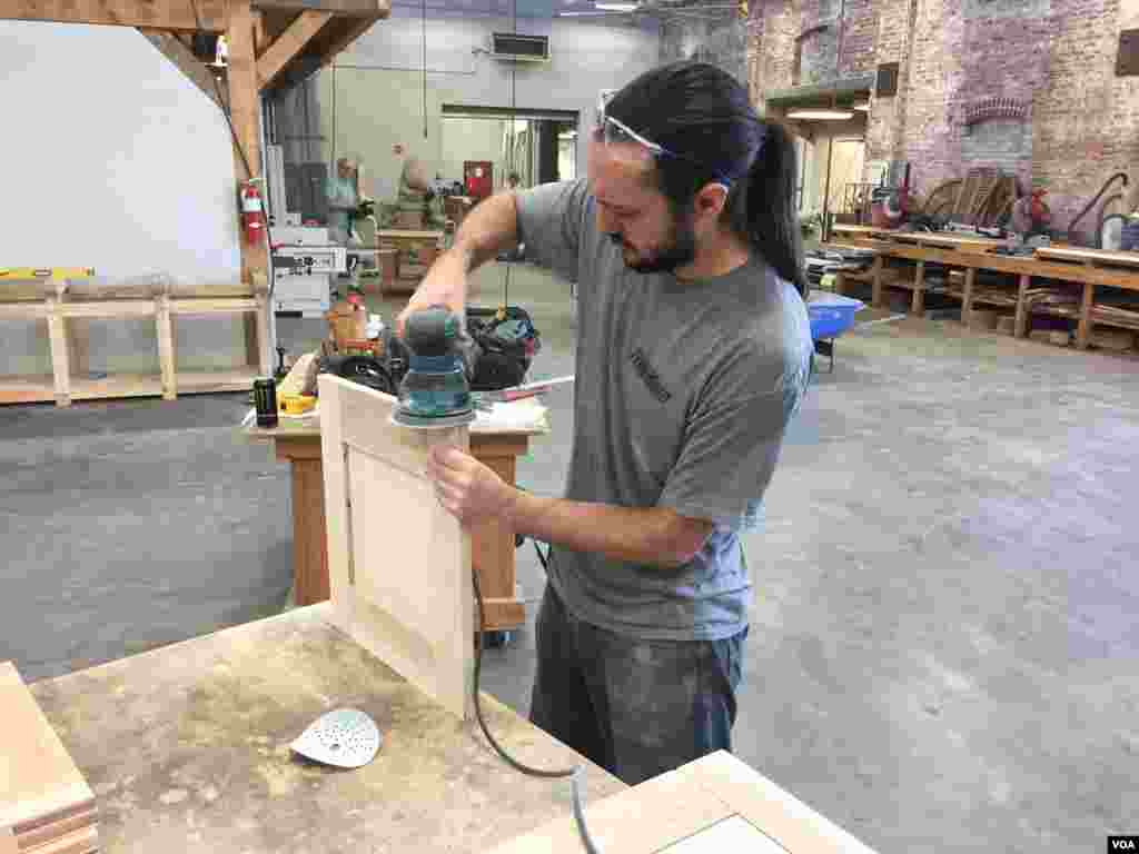 American College of the Building Arts sophomore Steven Fancsali sands a piece of wood for a workbench, in Charleston, S.C., Sept. 17, 2019. (J. Taboh/VOA News)