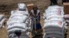 FILE—An Ethiopian woman stands by sacks of wheat to be distributed by the Relief Society of Tigray in the town of Agula, in the Tigray region of northern Ethiopia, May 8, 2021.