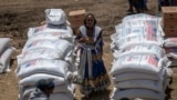 FILE—An Ethiopian woman stands by sacks of wheat to be distributed by the Relief Society of Tigray in the town of Agula, in the Tigray region of northern Ethiopia, May 8, 2021.