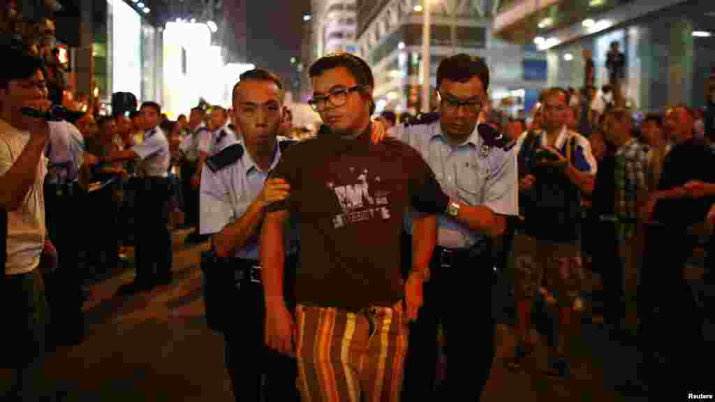 Police remove a pro-democracy protester from the area during confrontations between anti-Occupy Central protesters and pro-democracy protesters on a main street at Hong Kong's Mongkok shopping district, Oct. 3, 2014. 