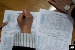 FILE - Nicole Motta, whose Korean name is Jang Hyeon-jung, fills out paperwork for a DNA test in Seoul, South Korea, May 31, 2024, as she and her birth father are reunited for the first time since she was adopted by a US family in 1985.