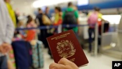 ARCHIVO - En esta foto tomada el miércoles 25 de junio de 2014, un pasajero sostiene su pasaporte venezolano mientras se prepara para viajar a Venezuela en el Aeropuerto Internacional de Miami.