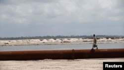 FILE - A man walks on a pipeline on the outskirt of Nigeria's commercial capital Lagos, June 25, 2016.