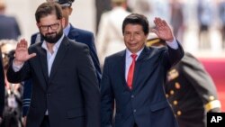 El presidente de Chile, Gabriel Boric, a la izquierda, y el presidente de Perú, Pedro Castillo, saludan a los periodistas cuando Castillo llega al palacio presidencial de La Moneda en Santiago, Chile, el martes 29 de noviembre de 2022. 