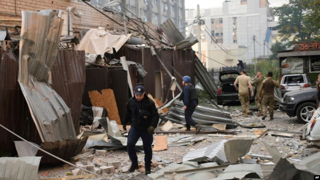 Seorang polisi dan petugas penyelamat berjalan di depan restoran RIA Pizza yang hancur akibat serangan Rusia di Kramatorsk, Ukraina, Selasa, 27 Juni 2023. (Foto: via AP)