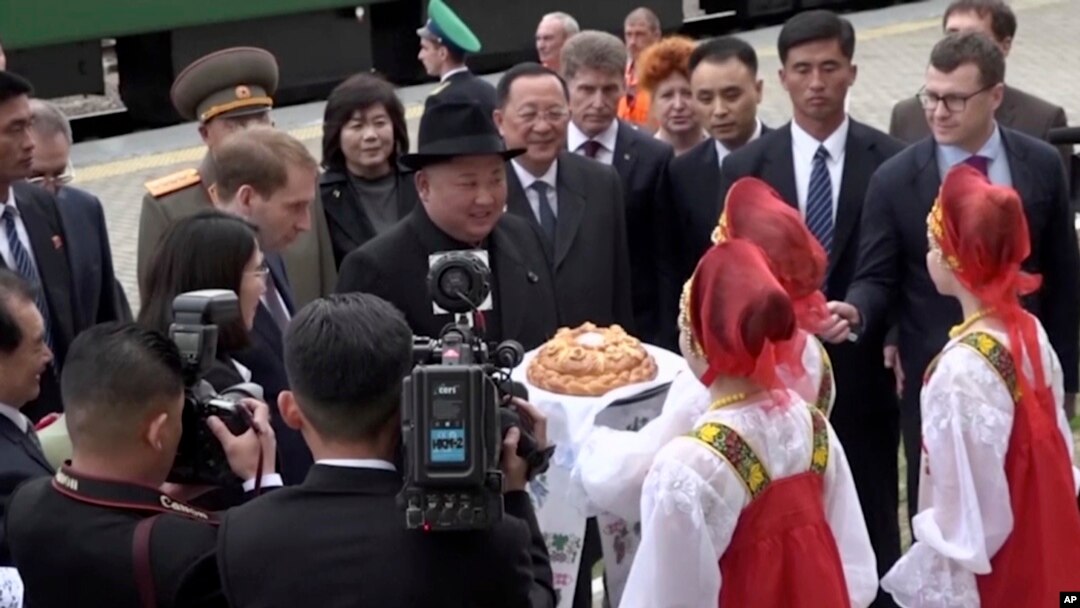 Pemimpin Korea Utara, Kim Jong-un (tengah) disambut oleh gadis-gadis berpakaian tradisional Rusia setibanya di stasiun kereta Khasan di wilayah Primorye, Rusia, Rabu, 24 April 2019.