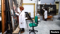 Restorers Alessandra Zarelli and Rossana Giardina work on paintings at the "painting and wood materials restoration laboratory" inside the Vatican Museums, at the Vatican, December 11, 2023. (REUTERS/Guglielmo Mangiapane)