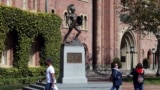 FILE - Students walk in front of the Trojan statue at the University of Southern California. The school will be one of the most costly in the U.S. next year. (AP Photo/Reed Saxon, File)