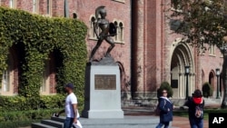 FILE - Students walk in front of the Trojan statue at the University of Southern California. The school will be one of the most costly in the U.S. next year. (AP Photo/Reed Saxon, File)