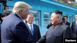 Mantan Presiden AS Donald Trump (kiri) berjabat tangan dengan pemimpin Korea Utara Kim Jong Un ketika mereka bertemu di zona demiliterisasi (DMZ) yang memisahkan antara Korea Utara dan Korea Selatan, di Panmunjom, Korea Selatan, pada 30 Juni 2019. (Foto: KCNA via Reuters)