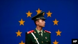 FILE - A Chinese paramilitary policeman stands on duty in front of a European Union flag outside the office of the European Union delegation to China, in Beijing, Oct. 28, 2011.