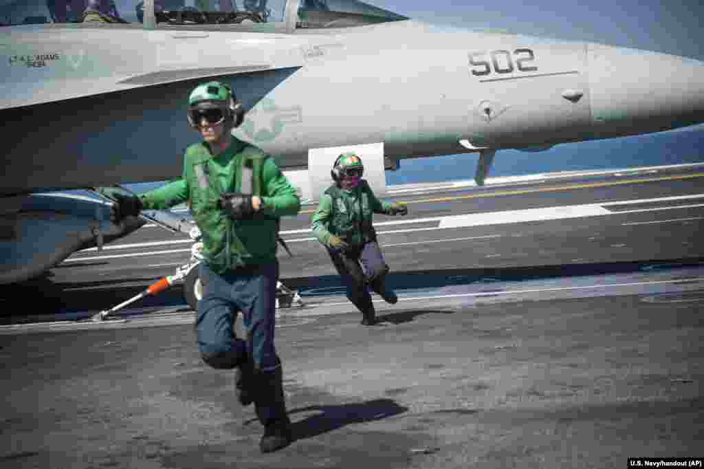 Sailors Aaron Jones, left, from Oceano, Calif., and Raime Baker, from Spanaway, Wash., clear the deck of the aircraft carrier USS Carl Vinson, currently deployed supporting strike operations in Iraq and Syria, a campaign formally named "Operation Inherent