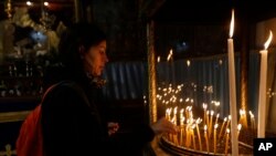 Seorang perempuan menyalakan lilin di Gereja Kelahiran Tuhan (Church of the Nativity), yang dibangun di atas tempat yang dipercaya oleh umat Kristiani sebagai tempat lahirnya Yesus Kristus pada malam Natal, di Tepi Barat Kota Bethlehem, Minggu, 24 Desember 2017.