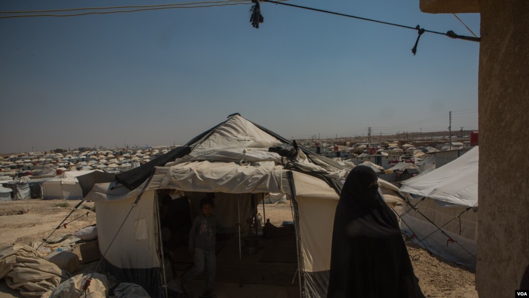 A woman walks among the thousands of tents at Al-Hol Camp. Here, the Islamic rules implemented by IS are still followed as they were under the group, Aug. 26, 2019. (Yan Boechat/VOA) 