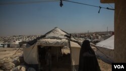 A woman walks among the thousands of tents at Al-Hol Camp. Here, the Islamic rules implemented by IS are still followed as they were under the group, Aug. 26, 2019. (Yan Boechat/VOA) 