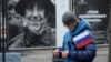 Un hombre lleva una bandera rusa frente a una exposición de fotografías callejeras del Ministerio de Defensa de Rusia que muestra a participantes de eventos en Ucrania, durante la celebración del Día de la Unidad Nacional en Rusia, 2023. [Foto: Archivo/AP]
