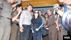 Buron terpidana kasus korupsi Kredit Likuiditas Bank Indonesia, Sherny Kojongian Saroha (tengah) dikawal oleh polisi saat tiba di Jakarta dari San Fransisco, AS, Rabu, 13/6 (foto: Andylala Waluyo).