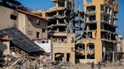 Warga Palestina mengendarai sepeda melewati bangunan yang hancur di Kota Gaza, 29 November 2023, hari keenam gencatan senjata sementara antara Hamas dan Israel. 