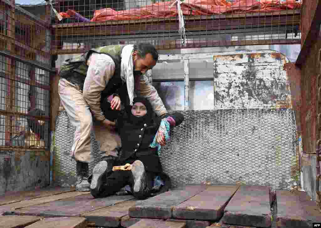 A wounded Syrian woman from the al-Sukari neighborhood is helped onto the back of a truck as she flees during the ongoing government forces military operation to retake remaining rebel-held areas in the northern embattled city of Aleppo.