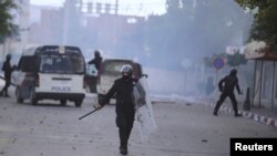 Riot police walk along a road during a protest in Kasserine, Tunisia, Jan. 20, 2016.