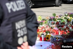 Policajac stoji pored cveća postavljenog na mestu gde su tri osobe ubijene, a nekoliko povređeno u napadu nožem na festivalu, u Zolingenu, Nemačka, 26. avgusta 2024. REUTERS/Jana Rodenbusch