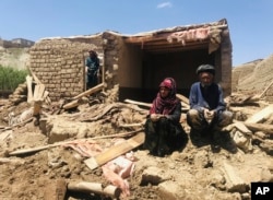 FILE—An Afghan couple sit near their damaged home after heavy flooding in Ghor province in western Afghanistan, May 18, 2024.