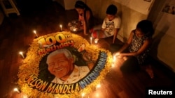 Children light candles beside a painting commemorating the 100th anniversary of South African revolutionary Nelson Mandela's birth at an art school in Mumbai, India, July 18, 2018. 