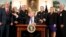 President Donald Trump, with Vice President Mike Pence, left, flanked by members of law enforcement, gestures while speaking before signing a bill in the Diplomatic Reception Room at the White House, June 2, 2017, in Washington. 