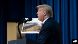 FILE - President Donald Trump speaks during a tours as he reviews border wall prototypes, Tuesday, March 13, 2018, in San Diego, as Rodney Scott, the Border Patrol's San Diego sector chief, listens. 