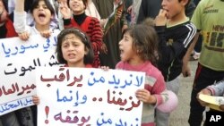 Demonstrators take part in a protest against Syria's President Bashar Al-Assad in Kafranbel, near Idlib May 1, 2012. Poster reads: "No need to observe our bleeding..we want who can stop it". 