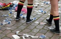 FILE - Two Belgian fans, wearing the Belgian colors, walk through plastic cups and other garbage after taking part in a celebration in Antwerp, Belgium, June 18, 2016.