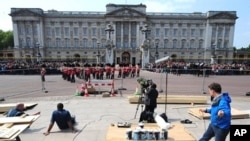 A TV crew works as members of the household brigade marching band walk in front of Buckingham palace, in London, on April 28, 2011.