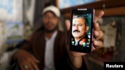 FILE - A man displays a picture of Yemen's former president, Ali Abdullah Saleh, on his mobile phone as he sits at a barber shop in the old quarter of Sana'a, Yemen June 16, 2015.