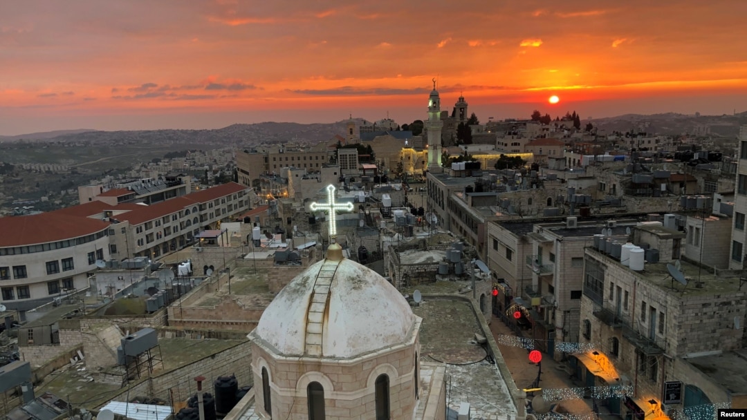 Kubah gereja Assyria menghadap menara masjid di Manger Square di Bethlehem di Tepi Barat yang diduduki Israel, 24 Desember 2018. (Foto: Reuters/Mustafa Ganeyeh)