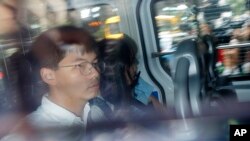 Pro-democracy activists Joshua Wong, left, and Agnes Chow, are escorted in a police van at a district court in Hong Kong, Aug. 30, 2019. 