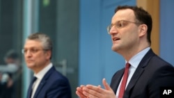 German Health Minister Jens Spahn, right, and Lothar H. Wieler, left, president of the Robert-Koch-Institute, address the media during a press conference in Berlin, Germany, Friday, March 12, 2021. (AP Photo/Michael Sohn, pool)