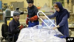 L'Iranienne Leila Daneshvar (à droite), directrice générale de KTMA (Kian Tajhiz Mehr Afarin), travaille avec des ingénieurs à l'usine de l'entreprise dans le quartier de Shahriar à Téhéran, le 17 mai 2018.