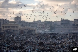 Birds fly over a pile of garbage, as there is no refuse collection in the city and people are disposing of their rubbish in the streets, in Gaza City, Feb. 12, 2025.