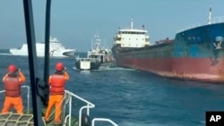 In this photo made from video released by the Taiwan Coast Guard, Taiwanese Coast Guard vessels prepare to board Togolese-flagged cargo ship Hongtai suspected of severing an undersea communications cable, Feb 25, 2025. 