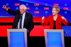 U.S. Senators Bernie Sanders, left, and Elizabeth Warren speak on the first night of the second 2020 Democratic presidential debate in Detroit, Michigan, July 30, 2019.