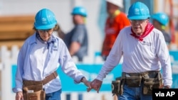 Antigo Presidente Jimmy Carter dá as mãos à sua esposa Rosalynn Carter enquanto trabalham com outros voluntários para Habitat for Humanity em Mishawaka, Indiana, Agosto 27, 2018. (Robert Franklin/South Bend Tribune)