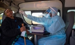 FILE - An elderly woman reacts as a health worker collects a sample for coronavirus testing during the screening and testing campaign aimed to combat the spread of COVID-19 at Sphamandla informal settlement in Katlehong, south of Johannesburg.