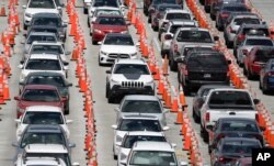 Lines of cars wait at a coronavirus testing site outside of Hard Rock Stadium, June 26, 2020, in Miami Gardens, Fla.