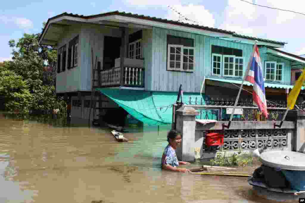 A woman floats through water in front of her flooded house, Ayutthaya, October 6, 2011. (VOA- D. Schearf)