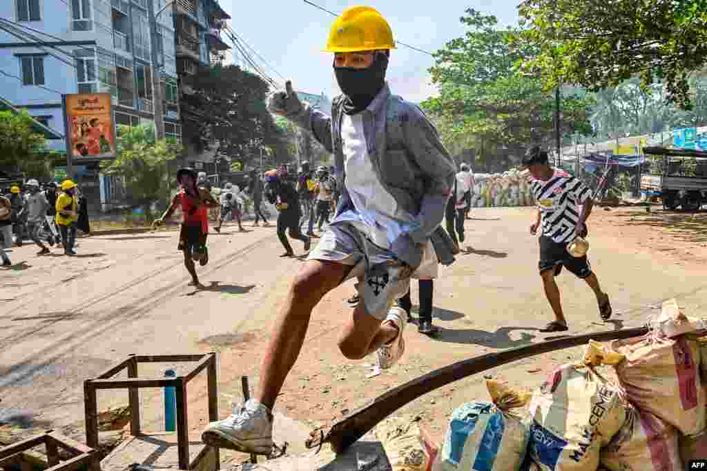 A protester jumps over a makeshift barricade during a crackdown by security forces on a demonstration against the military coup in Yangon&#39;s Thaketa township.